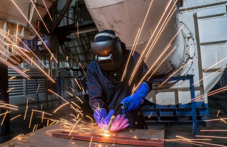 worker with protective mask is welding metal